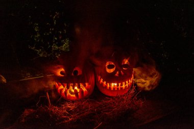 Cadılar Bayramı, karanlık arka planda korkunç bir yüzü olan yanan bir balkabağı, dışarı çıkan gri duman, Cadılar Bayramı zamanı, bir grup korkutucu balkabağı, sonbahar