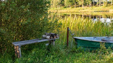 Küçük bir orman gölü, gölün kıyısında bir tekne, akşam ışığında saf bir göl, sakin bir yaz akşamı.