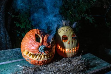 Cadılar Bayramı, karanlık arka planda korkunç bir yüzü olan yanan bir balkabağı, dışarı çıkan gri duman, Cadılar Bayramı zamanı, bir grup korkutucu balkabağı, sonbahar