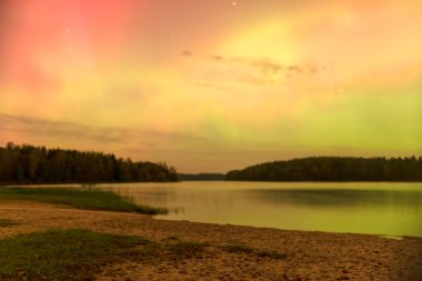 Gökyüzünde güzel kuzey ışıkları olan renkli fotoğraf gölün üzerinde kuzey ışıkları, Vaidavas Gölü, Letonya