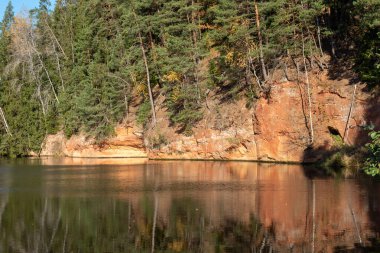 Brasla nehrinin kıyısında kumtaşı çıkıntıları, sonbaharda renkli ağaçlar, parlak renkler, Letonya, sonbahar