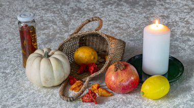 Beyaz bir masa örtüsü üzerinde hayat, hasır bir sepet içinde meyve ve diğer nesneler, siyah arkaplan