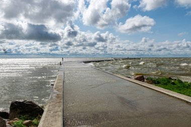 Deniz burnu, fırtına sırasında deniz, iskelede dalgalanan dalgalar, hızlı hareket eden bulutlar Litvanya 'daki Curonian Tükürüğü' nün yanındaki Cape Vente.