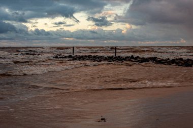 Baltık Denizi 'nde dramatik bir fırtına, taş iskeleye çarpan büyük dalgalar, bulanık, belirsiz hatlar, Vidzeme, Thuja, Letonya' nın kayalık kıyıları