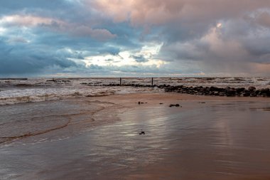 dramatic storm in the Baltic Sea, large waves crashing against the shore, blurred, unclear contours, rocky shore of Vidzeme, Thuja, Latvia clipart