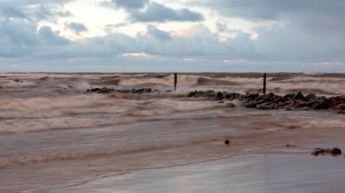 Baltık Denizi 'nde dramatik bir fırtına, taş iskeleye çarpan büyük dalgalar, bulanık, belirsiz hatlar, Vidzeme, Thuja, Letonya' nın kayalık kıyıları