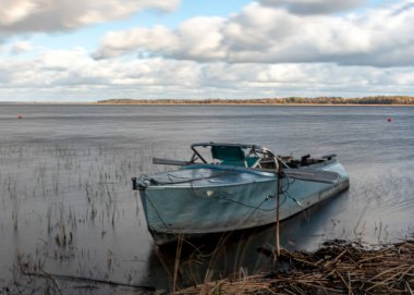 Göl kıyısındaki tekne, fırtına sırasında, su ve çimen hatlarını bulanıklaştırdı, Burtnieki Gölü, Letonya