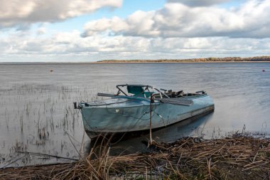 Göl kıyısındaki tekne, fırtına sırasında, su ve çimen hatlarını bulanıklaştırdı, Burtnieki Gölü, Letonya