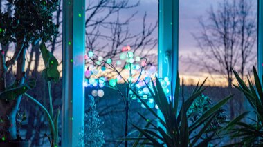 Pencerenin dışında renkli gündoğumu gökyüzü, renkli ışık oyunu, pencere camında gölgeler ve yansımalar, renk patlaması, kış