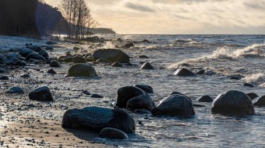 Deniz kıyısında kış manzarası, rüzgarlı kış günü, su damlaları, deniz kıyısında buzlu taşlar, Baltık Denizi, Letonya