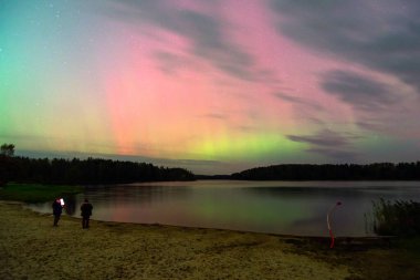 Gökyüzünde güzel kuzey ışıkları olan renkli fotoğraf gölün üzerinde kuzey ışıkları, Vaidavas Gölü, Letonya