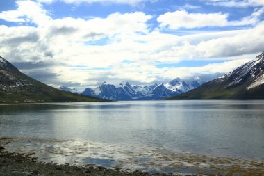 Nord summer Norwegian landscape behind the polar circle with green hills, sea bay, lake and houses near North Cape (Nordkapp), Finnmark in Norway