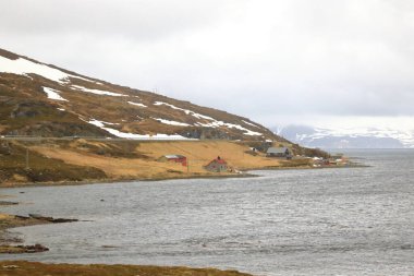 Nord summer Norwegian landscape behind the polar circle with green hills, sea bay, lake and houses near North Cape (Nordkapp), Finnmark in Norway