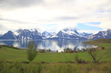 Nord summer Norwegian landscape behind the polar circle with green hills, sea bay, lake and houses near North Cape (Nordkapp), Finnmark in Norway