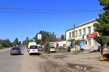 29 Ağustos 2023 - Kırgızistan 'da Ananyevo: Küçük şehirde arabaları ve dükkanları olan cadde üzerindeki manzaraya bakın
