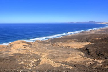 Playa de Cofete, Jandia, Fuerteventura, Canary Islands in Spain: Amazing beach behind the with stormy Atlantic Ocean, Volcanic hills in the background clipart