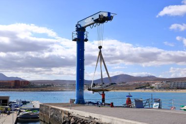 Caleta de Fuste, Fuerteventura, İspanya - 24 Kasım 2023: bir adam limanda basınç suyuyla bir sürat teknesini ovuyor.