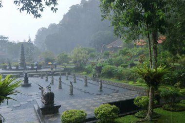 Bali, Endonezya - Şubat 05 2024: İnsanlar yağmurlu bir günde Doğu Bali 'deki Tirta Gangga Su Sarayı' nın tadını çıkarıyor