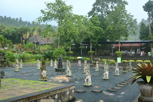 Bali, Endonezya - Şubat 05 2024: İnsanlar yağmurlu bir günde Doğu Bali 'deki Tirta Gangga Su Sarayı' nın tadını çıkarıyor