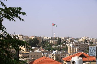 Amman, Jordan - May 18 2024: Large Jordanian flag flying over the city clipart