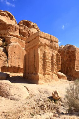 Cin blokları, üç devasa çömelmiş anıt, yolun kenarında nöbet tutuyorlar, Ürdün 'deki antik Petra kentinin girişinde.