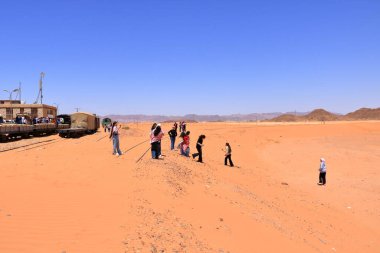 Ürdün 'deki Wadi Rum - 15 Mayıs 2024: İnsanlar neredeyse tamamen çöl kumuyla kaplı eski tren raylarını ziyaret ediyor.