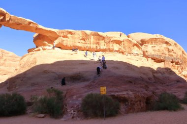 Ürdün 'deki Wadi Rum - 15 Mayıs 2024: Wadi Rum' daki Jebel Burdah kaya köprüsüne tırmanan insanlar