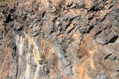 Gri kırmızı sarı kaya yüzlü, doğada bir dağ.