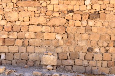 Sarı bej doğal taş duvar, farklı boyutlarda taşlar, geleneksel el sanatları.