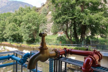 Les Escaldes - Engordany in Andorra - August 31 2024: The Caldes Art project with pipes and faucets at the River Valira clipart