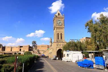 Erbil, Erbil, Kürdistan, Irak - 20 Kasım 2024: Şehir merkezindeki Şah Parkı 'nda saat kulesinin yanında dinlenen insanlar, Parki Sar