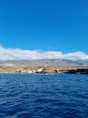 Costa del Silencio 'nun kıyı manzarası, deniz kenarında berrak mavi suları ve arka planda dramatik dağlık arazisi olan pitoresk bir köy. 
