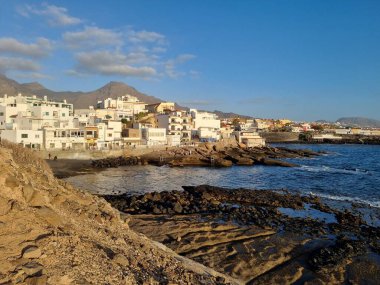 Tenerife 'deki Costa Adeje' nin güzel bir manzarası, kıyı şeridi boyunca uzanan kasaba, engebeli volkanik kıyı, ve açık mavi gökyüzünün altında muhteşem Teide Dağı..