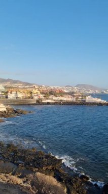 Canlı bir Tenerife kıyı şeridi, körfez boyunca uzanan bir yat, pitoresk plaj ve uzaktan görülebilen çarpıcı Teide volkanı, ideal bir tropikal kaçış sunuyor..