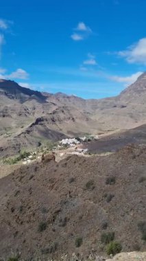 Tenerife 'deki El Molino de Viento bölgesinin çarpıcı manzarası, dramatik dağlar ve açık mavi gökyüzüyle çevrili, kırsal manzarayı ve aşağıdaki köyü gösteriyor..
