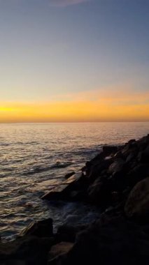 Güneş ufukta batarken sakin bir Tenerife gün batımı okyanusu altın rengine boyar. Huzurlu deniz yavaşça kıyıya doğru döner ve sahilde huzurlu bir an yaratır.