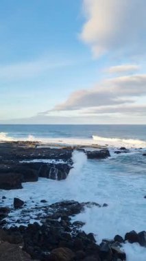 Charco del Viento 'da Tenerife' nin çarpıcı kıyı şeridi, güçlü dalgalar siyah volkanik kayalara çarpıyor, nefes kesen okyanus manzarası ve açık gökyüzü sunuyor..