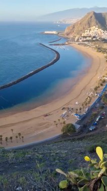 Playa de las Teresitas, Tenerife 'de yer alan temiz turkuaz suyu ile güzel bir altın kumsal. Etrafı yemyeşil dağlarla çevrili, rahatlamak ve güneşlenmek için mükemmel bir sahil kaçamağı sunuyor..