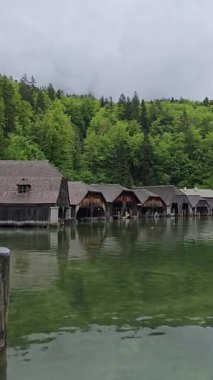 Berchtesgaden 'deki Koenigssee Gölü' ndeki geleneksel ahşap kayıkhaneler sisli Bavyera Alpleri ve Almanya 'nın ikonik ulusal parkındaki sık ormanlarla çevrili..