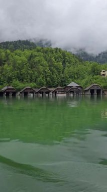 Berchtesgaden Ulusal Parkı, Almanya 'da, Berchtesgaden Ulusal Parkı' ndaki gür ormanlar ve sisli Bavyera Alpleriyle çevrili zümrüt göl üzerindeki ahşap kayıkhanelerin manzarası..