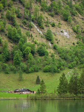 Berchtesgaden Ulusal Parkı, Bavyera Alpleri, Yukarı Bavyera, Almanya 'da Alp Dağları ve yemyeşil çayırlar tarafından kucaklanan Obersee kıyısındaki bir kır evi..