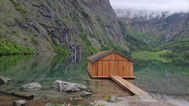 Obersee Gölü 'ndeki büyüleyici ahşap kayıkhane, Berchtesgaden Ulusal Parkı' nın çarpıcı doğal güzelliğinde, Almanya 'nın Bavyera kentindeki bereketli dağlar ve kristal berrak sularıyla..