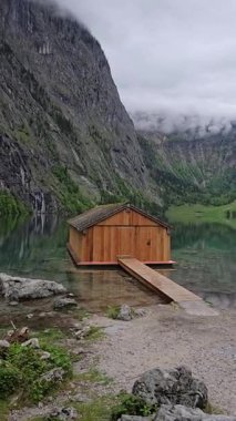Obersee Gölü 'ndeki ahşap kayıkhane, Berchtesgaden Ulusal Parkı, Bavyera' da yüksek uçurumlar ve yemyeşil alanlarla çevrili.