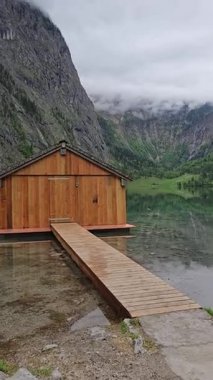 Berchtesgaden Ulusal Parkı, Bavyera, Almanya 'nın görkemli uçurumları arasında yer alan Obersee Gölü' nün sakin kıyılarındaki ahşap kayıkhane..