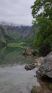 Berchtesgaden Ulusal Parkı 'ndaki berrak Obersee Gölü, dağlar ve bulutlarla çevrili. Almanya 'nın Bavyera Alpleri' nde huzurlu, manzaralı bir manzara.