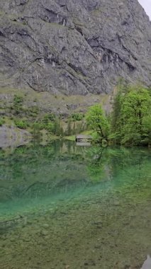 Berchtesgaden Ulusal Parkı, Yukarı Bavyera 'daki yemyeşil orman ve dağlarla çevrili zümrüt yeşili Obersee' nin uzak kıyısında küçük bir ahşap kayıkhane sessizce uzanır..