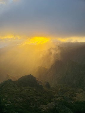 Güneş ışığı, Pico do Arieiro 'daki yumuşak bulutları delip geçiyor. Altından, dingin bir ışıltıyla parlıyor. Engebeli araziyi sıcacık ve aydınlık bir şekilde kucaklıyor..