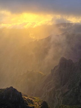 Pico do Arieiro 'da bulutlar sürükleniyor. Altın güneş ışığı gökyüzünü delip geçiyor. Engebeli dağları huzur dolu, ışıl ışıl parlıyor..