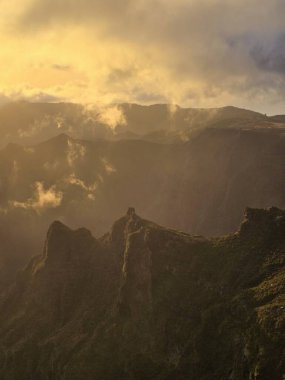 Pico do Arieiro 'da altın bir sabah, bulutlar parlayan tepeleri ve güneşli tepeleri ortaya çıkarmak için ayrılırken, dağ sahnesini sıcak ve huzurlu bir güzellikle dolduruyor..