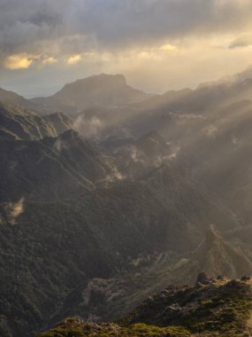 Pico do Arieiro 'nun engebeli arazisinin üzerindeki bulutlarda güneş ışığı Madeiras volkanik tepeleri boyunca nefes kesen bir ışık ve gölge etkileşimi yaratır..